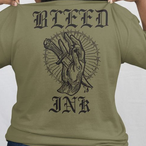 Green t-shirt with black graphic design and 'BLEED INK' text on a plain background