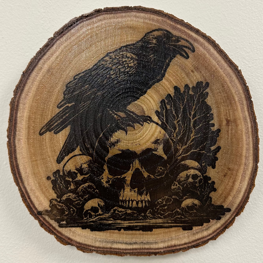 Close Up - Top View
Round - Wooden Plaque with a carved design of a crow and skulls on a light background.