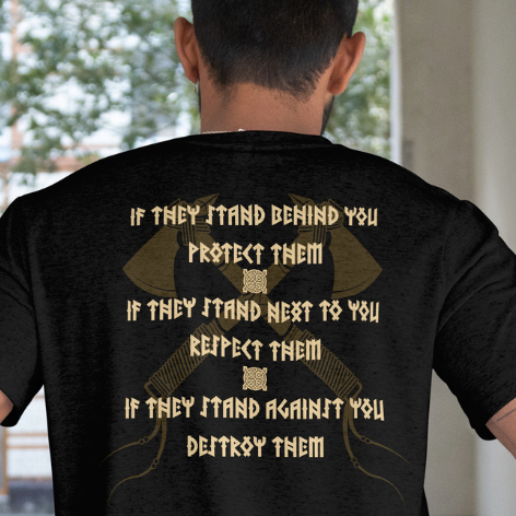 Close Up - Back View
Person wearing a black t-shirt with gold text and design on the back, standing in a room with a window.