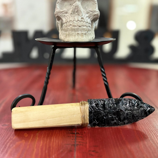 Close up
Decorative item with wooden handle and black decorative element on a red surface, skull in the background. Obsidian Knife.