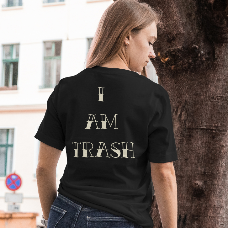 Back View worn by model.
Person wearing a black t-shirt with 'I AM TRASH' text on the back, standing outdoors.