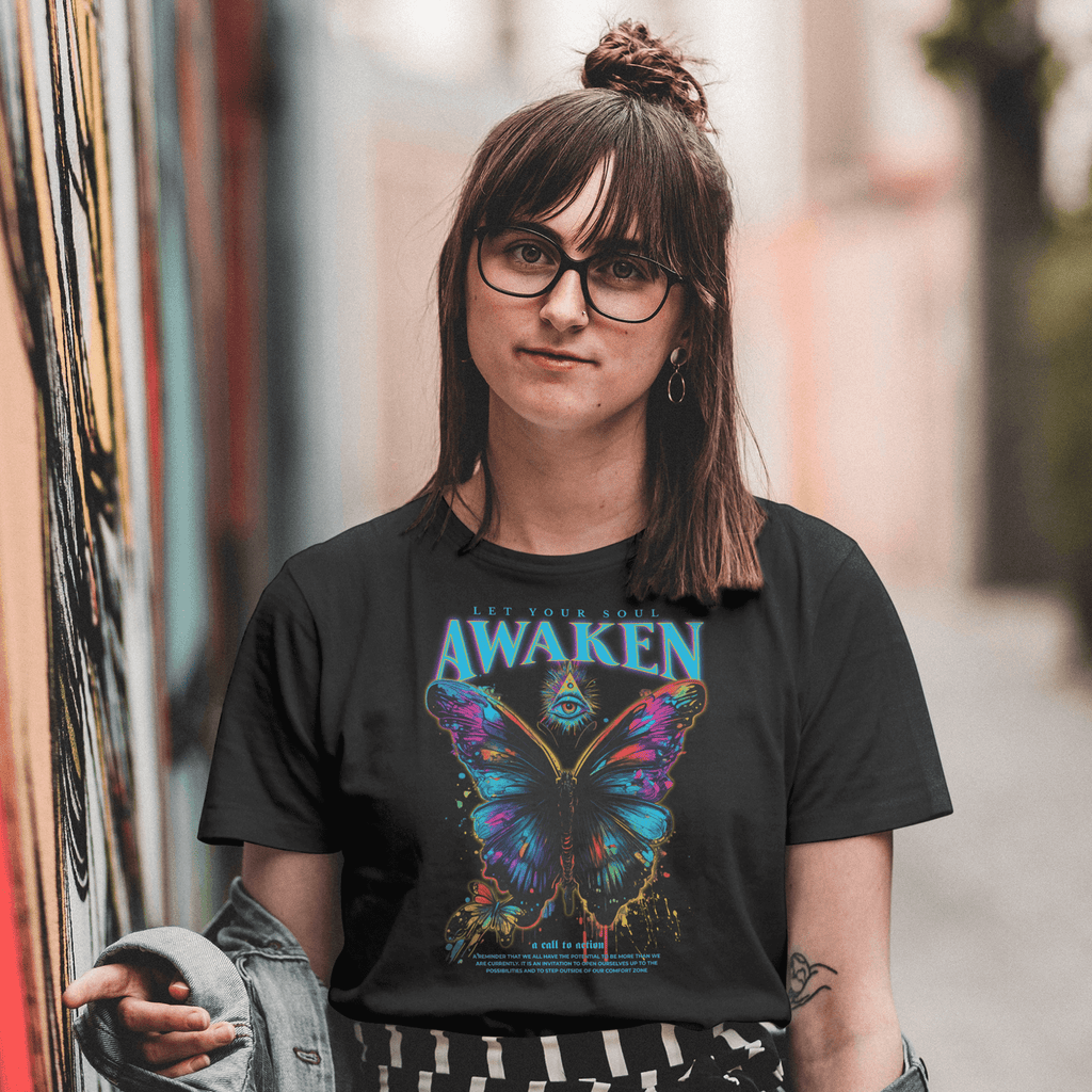 Person wearing a black t-shirt with a colorful butterfly graphic and 'Awaken' text, standing in an urban setting.