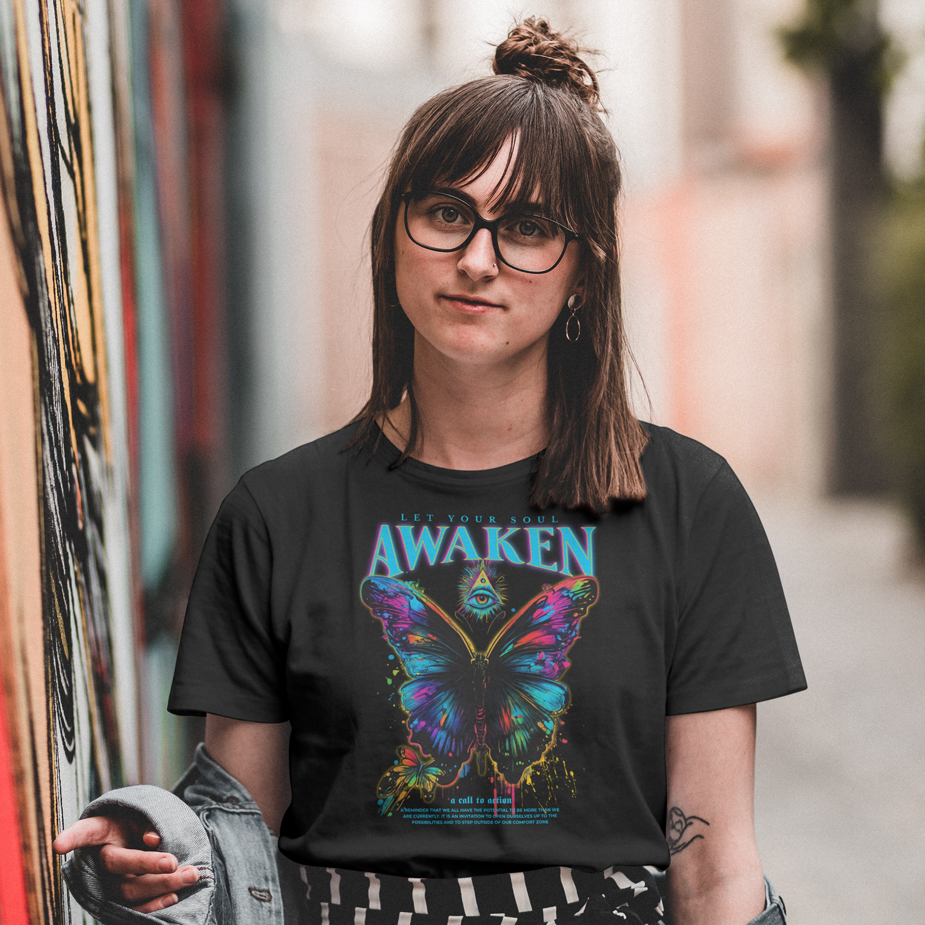 Person wearing a black t-shirt with a colorful butterfly graphic and 'Awaken' text, standing in an urban setting.