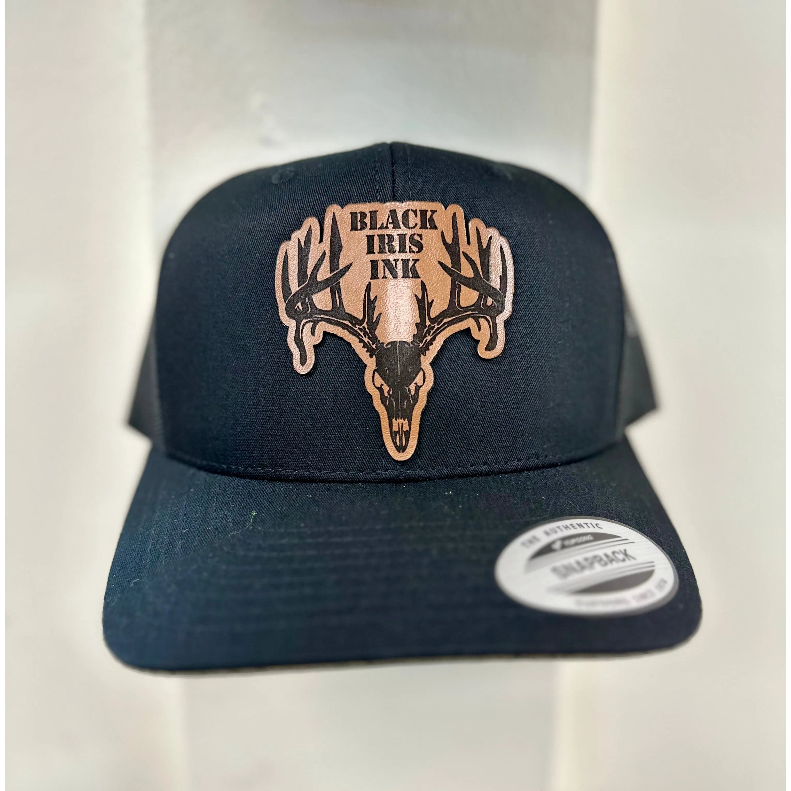Close up
Black cap with deer skull design and 'Black Iris Ink' logo on a white background