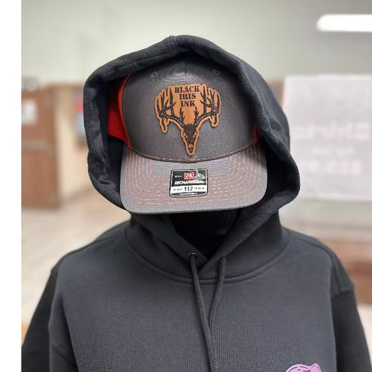 Heather gray and neon orange trucker hat with genuine leather deer skull patch on front panel

