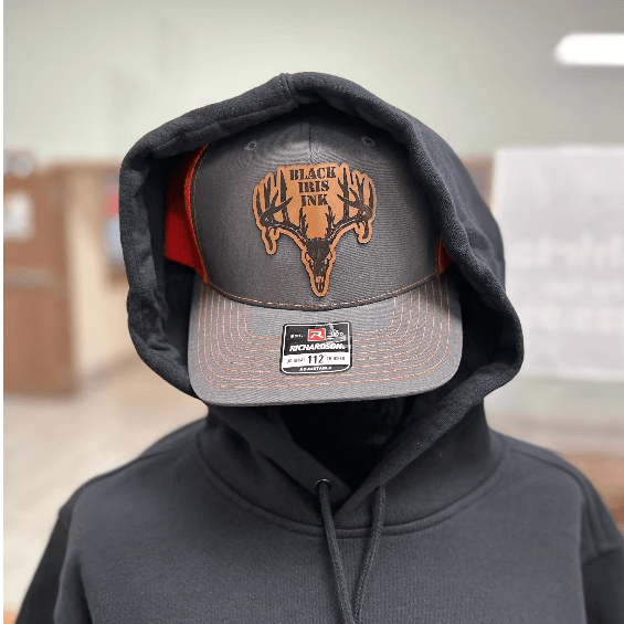 Heather gray and neon orange trucker hat with genuine leather deer skull patch on front panel

