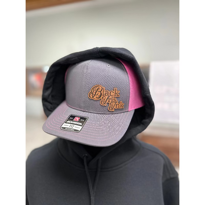 Heather-gray and Neon-Pink hat with a free-form leather patch that Reads Black Iris Ink.