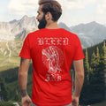Red Bleed Ink T-Shirt Tattoo Inspired featuring bold artwork on the back of a red shirt against a mountain backdrop.