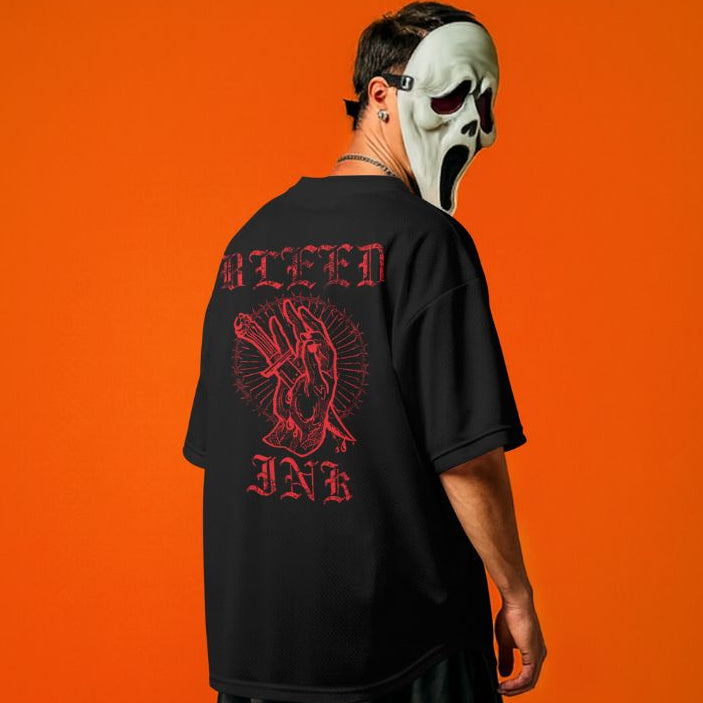 Back View
Person wearing a black t-shirt with red graphics and text, 'Bleed Ink' standing against an orange background