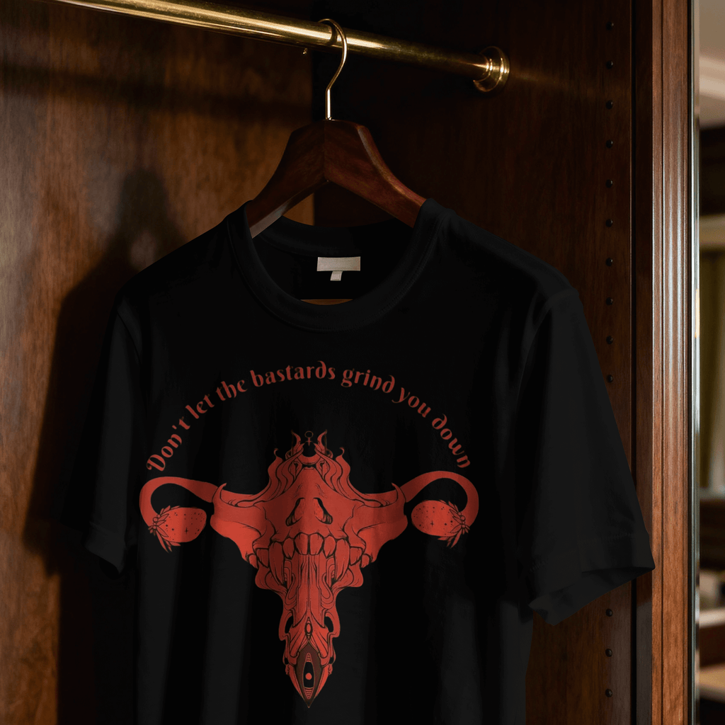 Black t-shirt with red graphic and text on a hanger against a wooden door.