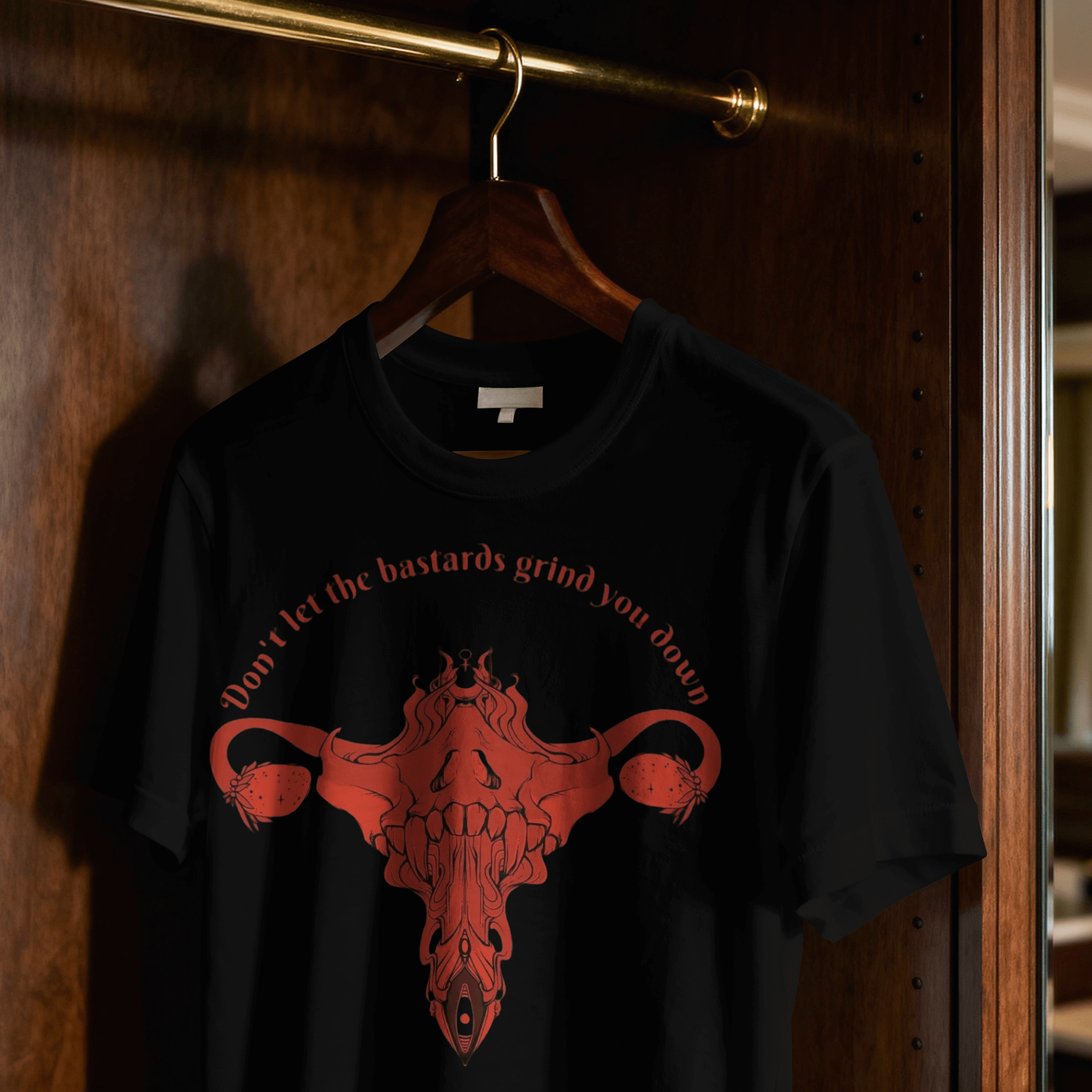 Black t-shirt with red graphic and text on a hanger against a wooden door.