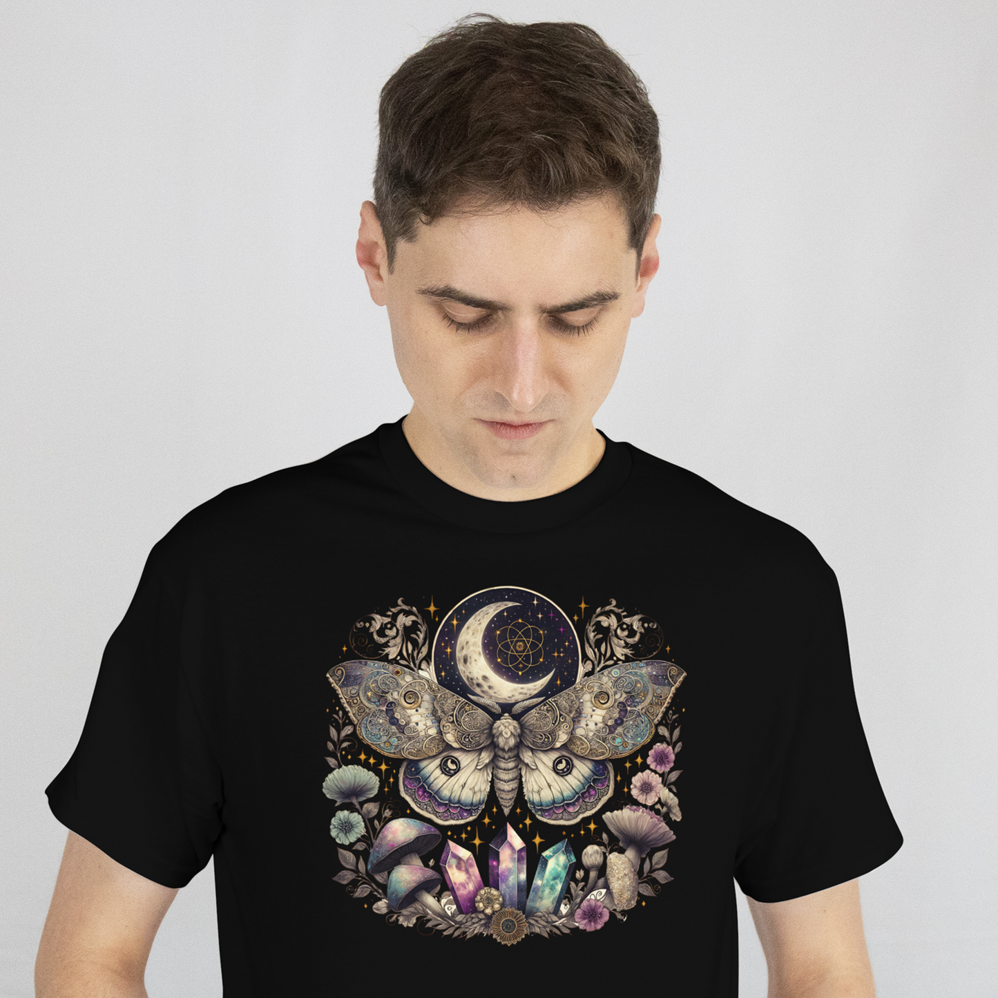 Man wearing a black t-shirt with a colorful moth and moon design on a plain background