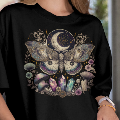Close Up - Front View on a model
Black t-shirt with a moth and moon design worn by a person.