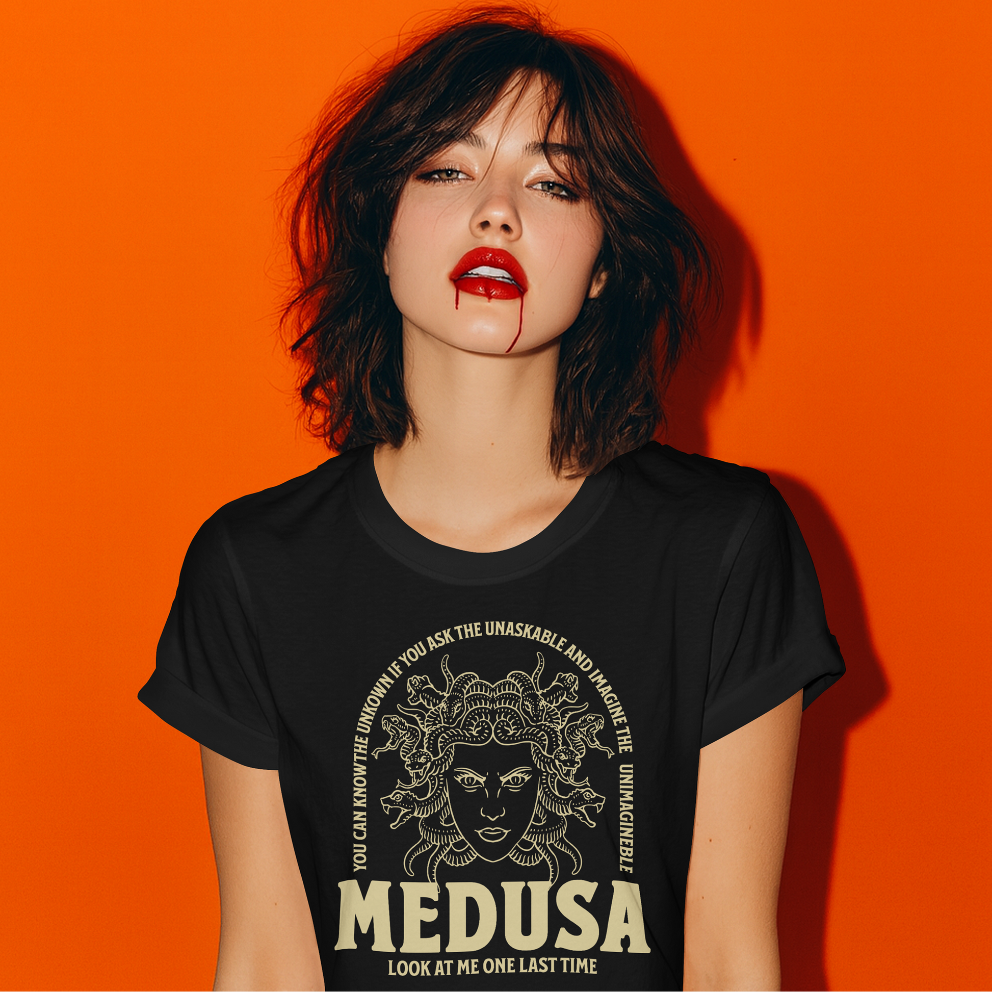 Woman wearing a black t-shirt with Medusa graphic against an orange background