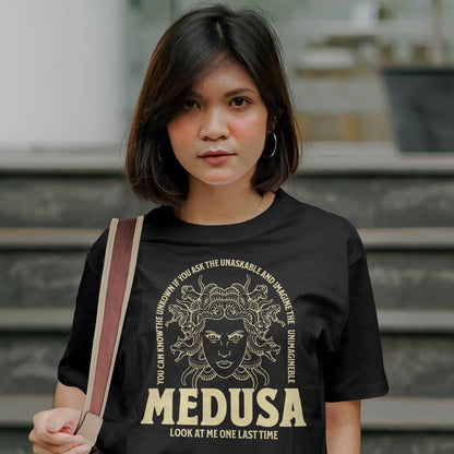 Woman wearing a black t-shirt with 'MEDUSA' design and text, standing outdoors.