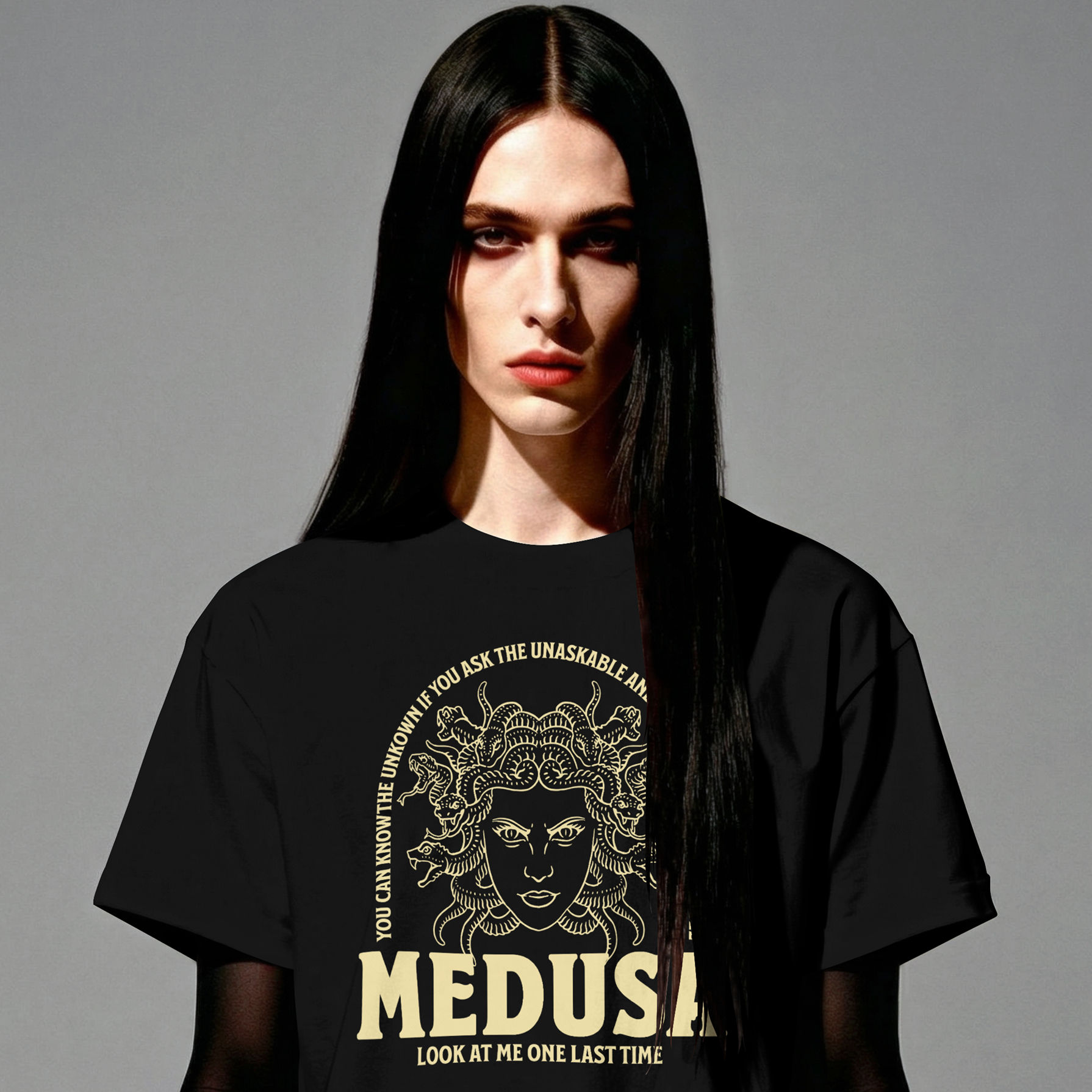 Person wearing a black t-shirt with Medusa graphic and text on a gray background