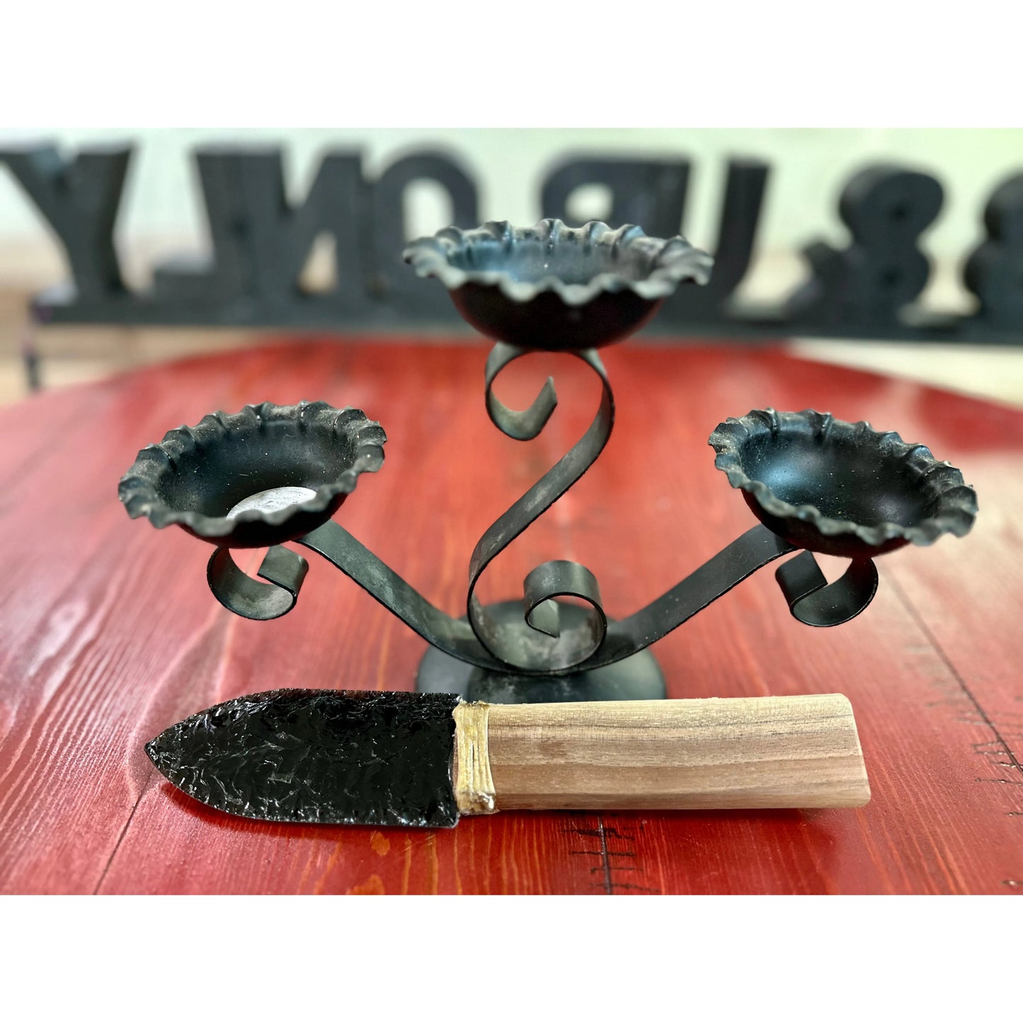 Obsidian knife next to a wrought iron candle holder. 