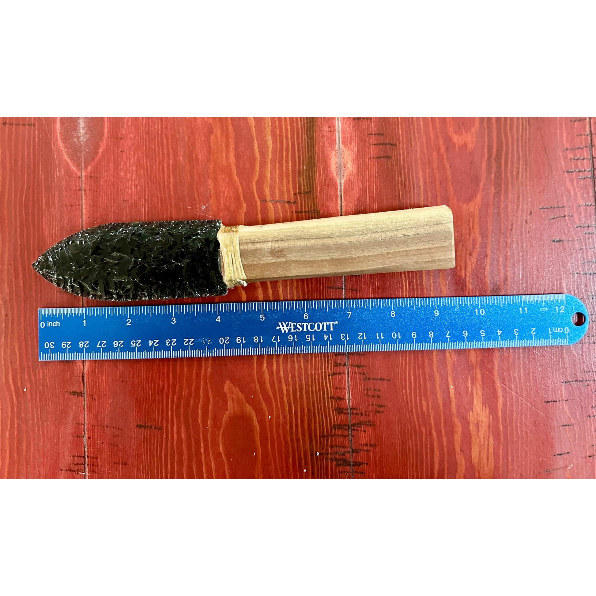Obsidian knife with wooden handle on a wooden surface next to a Westcott ruler