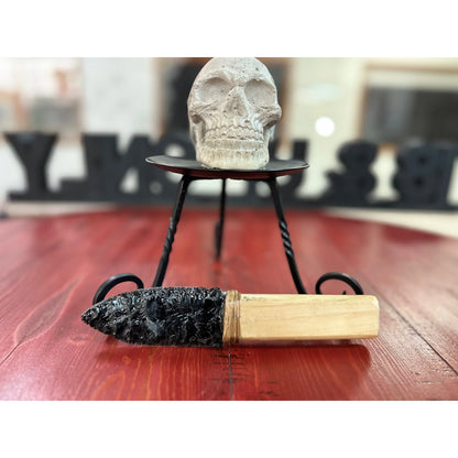 Skull on a stand with a hand Carved Obsidian kinfe  device on a wooden surface decorative purposes only.