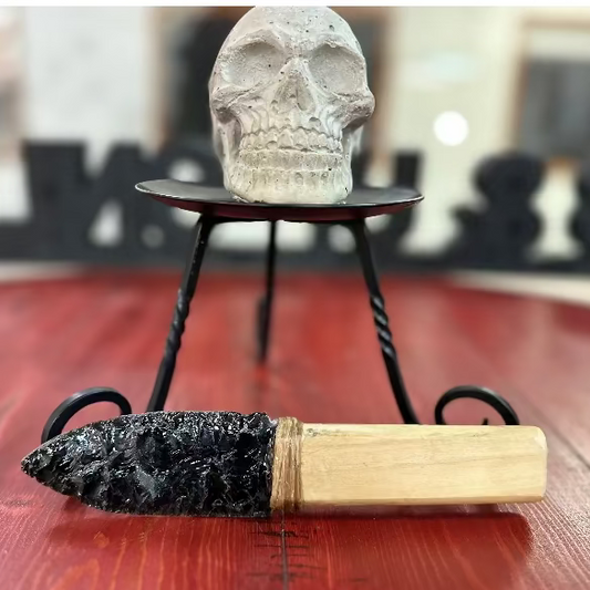 Skull on a stand with a hand Carved Obsidian knife  device on a wooden surface decorative purposes only.