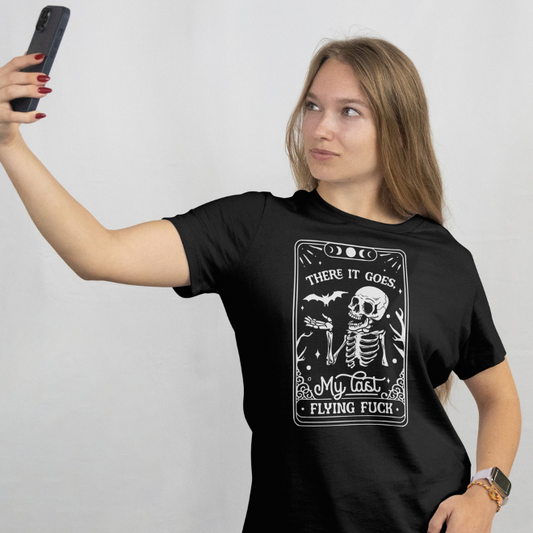 Front View worn by model.
Woman wearing a black t-shirt with graphic design and text, "There it goes my last flying fuck" taking a selfie against a plain background