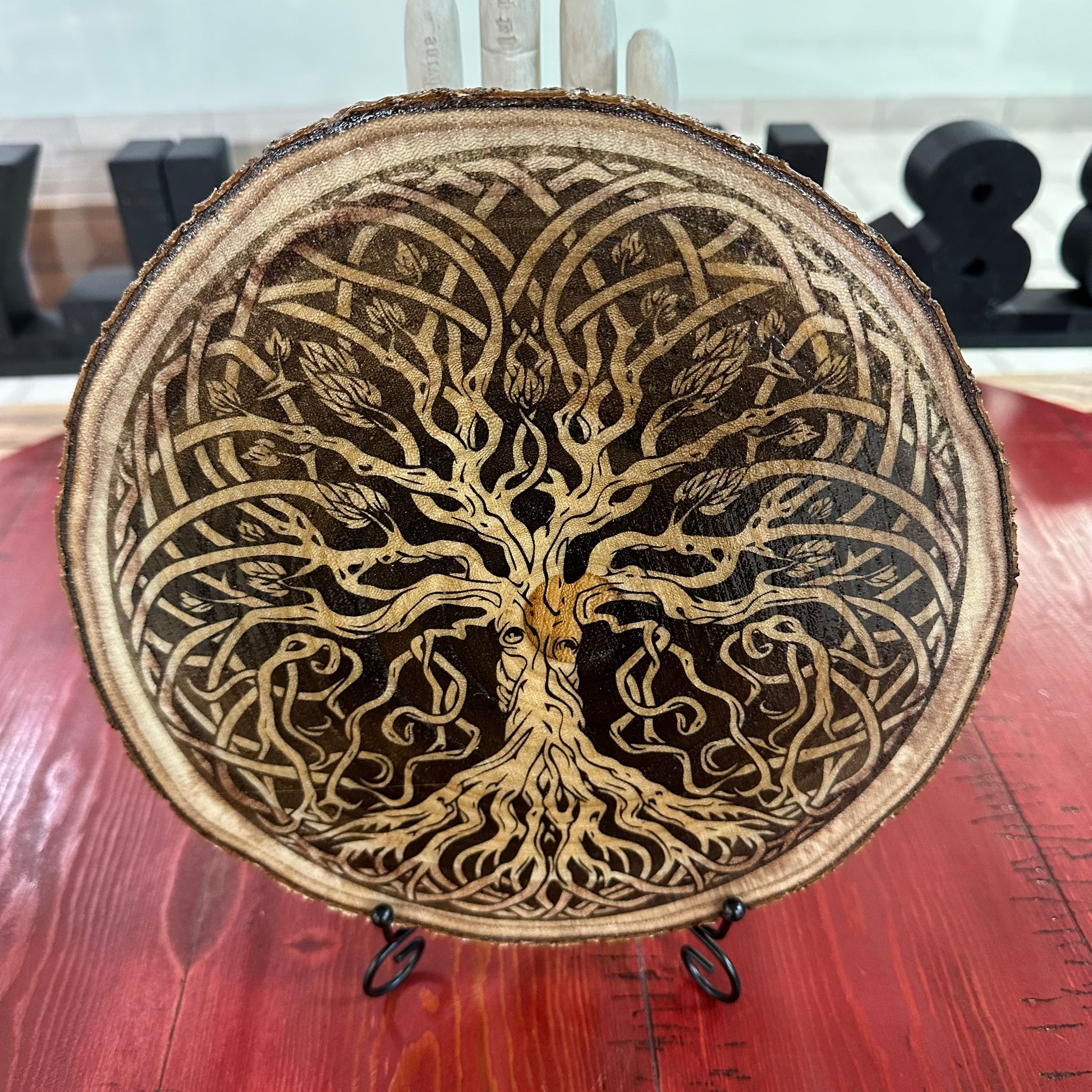 Close Up - Front View on a stand
A Rustic-round Decorative object with intricate tree-of-life design on a wooden surface. 