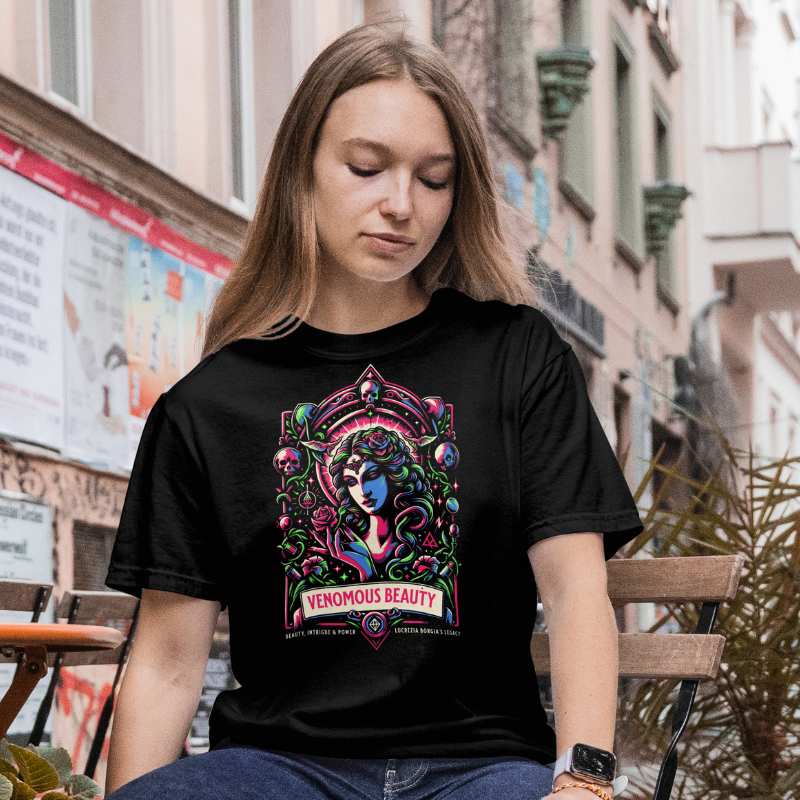 Woman wearing a black t-shirt with colorful graphic design 'Venomous-Beauty' sitting outdoors.