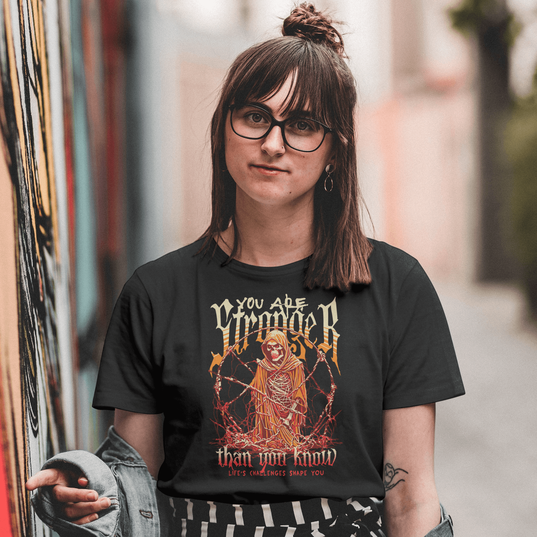 Person wearing a black t-shirt with a graphic design and text, standing in an alleyway.
